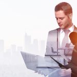 Businessman using laptop and holding contract on abstract office and city background with copy space. Finance and technology concept. Double exposure
